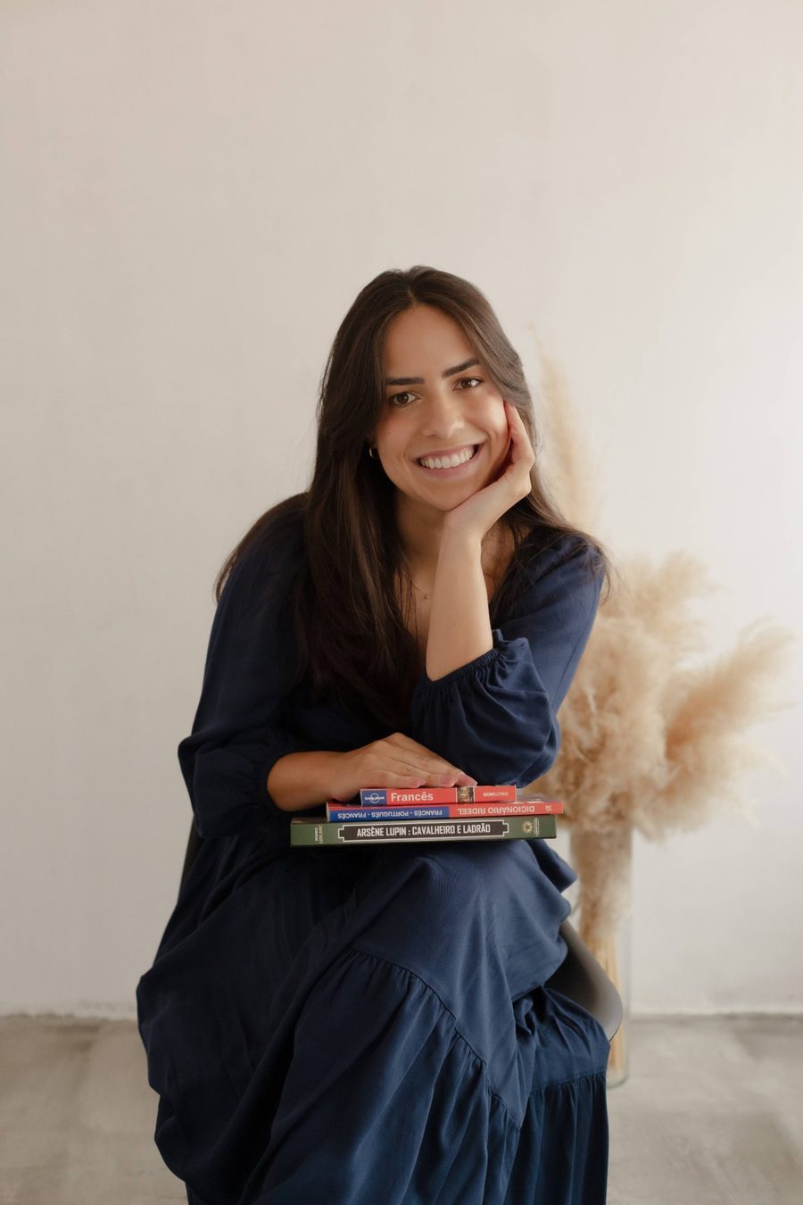 Professora Leri sorrindo, com livros de francês no colo